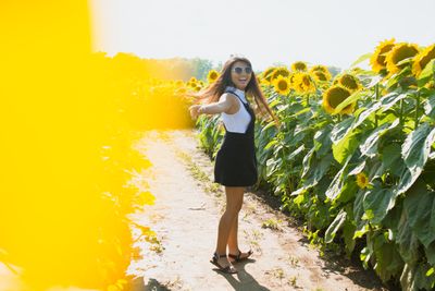 woman wearing sunglasses standing in a field of sunflowers